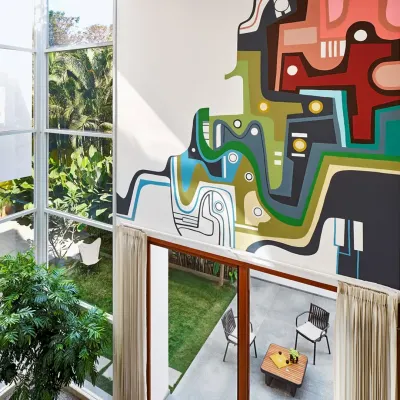 An aerial view of the Split House, highlighting the double-height living space and the vibrant custom mural. The large glass walls open up to the garden, ensuring the home is always connected to the outdoors.