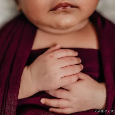 A macro shot of a newborn's tiny, clasped hands while swaddled in a deep purple wrap. These are the details that change so quickly, and I love preserving them.