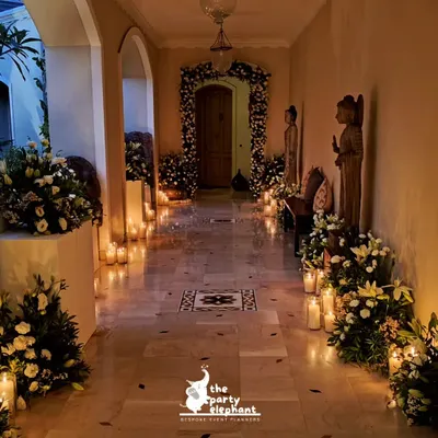 For this intimate wedding, I created a romantic candlelit hallway to welcome guests. The path was lined with large pillar candles and lush arrangements of white flowers, leading to a beautifully decorated floral archway.