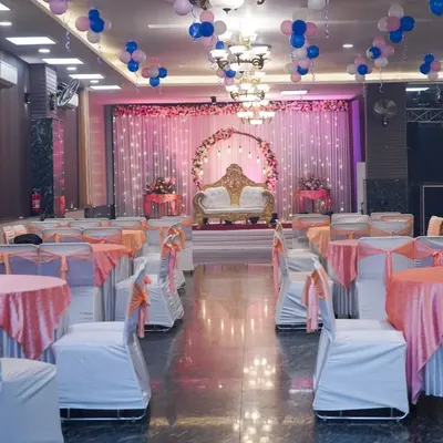 A wide-angle shot of a beautifully decorated wedding hall, showing the stage, seating arrangement, and balloon decorations before the guests arrive.