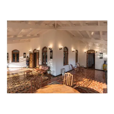 A wide view of the main hall in our Lonavala restoration project, where we balanced the structure's colonial and Indo-Saracenic influences with restored antique furniture and contemporary lighting to create a harmonious living space.