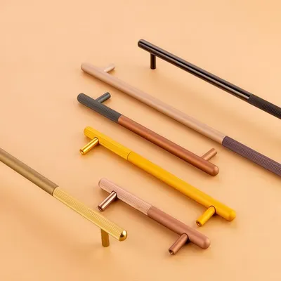 A collection of modern, dual-tone cabinet handles for Gauri Enterprises. The clean, flat-lay composition on a neutral background highlights their sleek design and color variations.