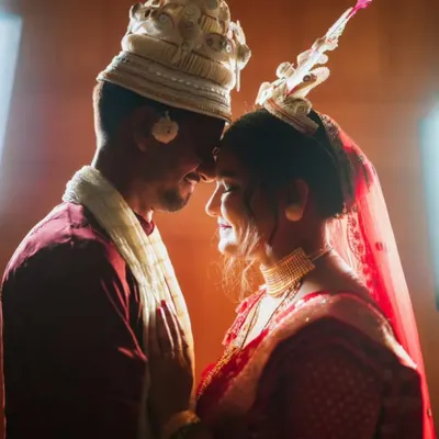 An intimate, beautifully lit portrait of a Bengali bride and groom in their traditional 'topor' and 'mukut'.