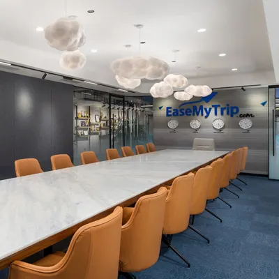 The main conference room features whimsical cloud lighting over a sleek marble table, set against a deep blue carpet. This room is designed to be the creative heart of the office, where big ideas can take flight.