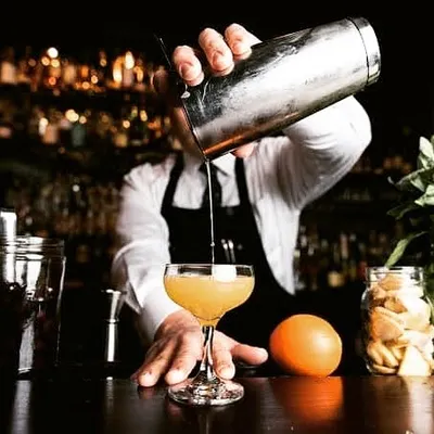 A classic cocktail being shaken and poured by a professional bartender. This shot captures the focus and expertise that goes into making a perfectly balanced drink.