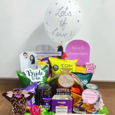 Here is a fun and vibrant hamper celebrating the bride-to-be. It's filled to the brim with her favorite snacks, chocolates, and cookies, complete with a personalized photo and a "Lots of Love" balloon to make her feel cherished as she counts down to her big day.