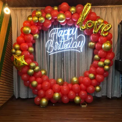 This circular balloon backdrop is a popular choice for romantic birthday parties. The mix of red and gold balloons with the bright neon sign provides a vibrant and festive focal point for any room.