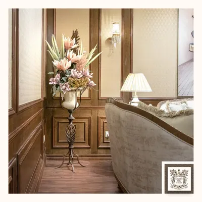 This elegant floral display, set in a classic urn on a sleek metal pedestal, is designed to be a standout piece in a corner or entryway. The arrangement adds height, color, and sophistication to the room.
