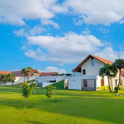 The campus of Vellore International School in Chennai, with its distinctive sloping tiled roofs and buildings set within a vast green landscape. The design creates a human-scaled, unintimidating environment for young students.