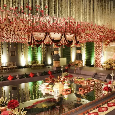 The central mandap area, set over a mirrored surface reflecting the stunning floral ceiling. Inspired by the Brihadishwara Temple, this design features tiered seating for guests, intricate floral pathways, and towering deity paintings, creating a 360-degree immersive experience.