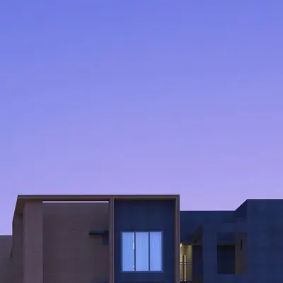 An abstract view of a building at twilight, where the simple geometry of the structure is silhouetted against a deep purple sky, creating a moment of quiet beauty.