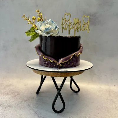 This modern Roka cake features a rich, dark chocolate finish with a stunning purple geode-style fault line, edged in gold. The design is finished with a delicate sugar flower and a fun 'Rokafied' acrylic topper.