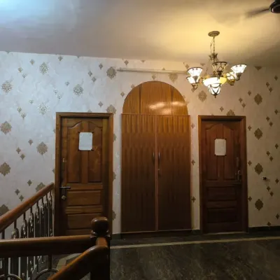 An elegant, light-colored damask wallpaper with a subtle gold motif, installed in a hallway and staircase area.
