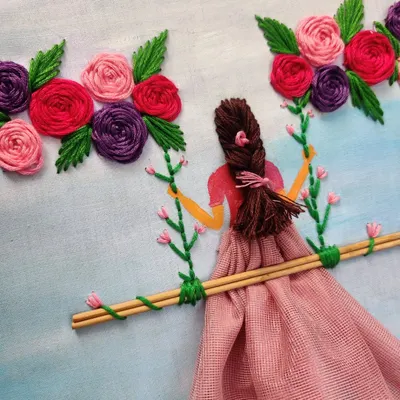 This is a mixed-media embroidery piece I created, featuring a girl on a swing. I used thread for her hair and the flowers, and a piece of fabric for her dress to give it a 3D effect.