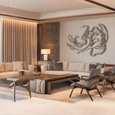 A living room at DLF Camellias where contemporary design meets Indian elements. The neutral sofa is accented with colorful cushions, while the back paneling highlights a stunning metal artwork, creating a space that is both modern and rooted.