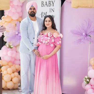 A beautiful portrait of the happy couple at their "Baby in Bloom" themed baby shower. Their coordinated outfits and the stunning balloon decor create a perfect memory of this special celebration.
