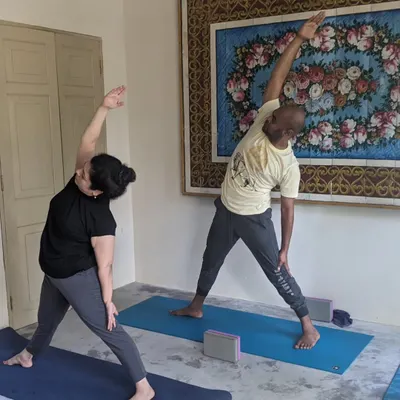 Two students moving through Trikonasana, or Triangle Pose, during an indoor session on our retreat. Even when we practice inside, the focus is on mindful movement and supporting each other's journey.