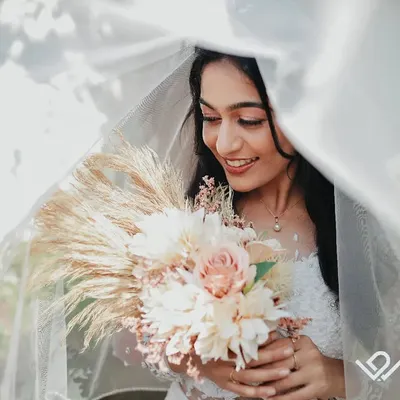 A Christian bride smiles softly under her veil, holding a beautiful bouquet. I use natural light to create these dreamy, romantic bridal portraits.