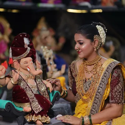A traditional look for welcoming Ganpati, featuring a bright yellow Nauvari with a maroon blouse and authentic temple jewellery.