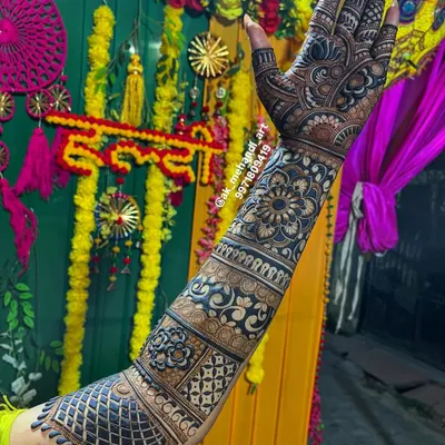 A full bridal arm design against a vibrant Haldi ceremony backdrop. I combine various patterns like jaal, paisleys, and floral bands to create a rich and cohesive look that extends up the arm.