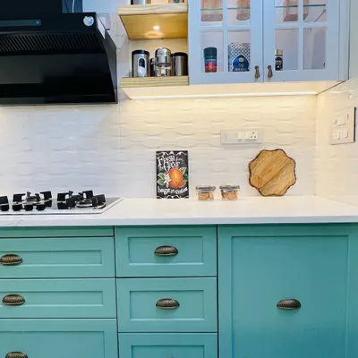 A beautiful and functional kitchen featuring two-toned cabinets in a lovely sea-green and white. The design includes open shelving for easy access and under-cabinet lighting for a bright workspace.
