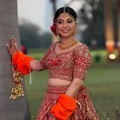 A beautiful outdoor shot of my bride, looking radiant and happy. Her classic red lehenga is paired with soft, glowing makeup.