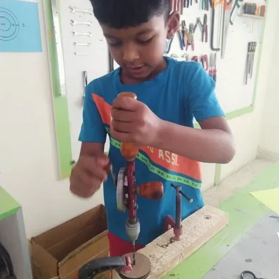 Using a hand drill requires focus and two hands. We teach kids the proper technique, ensuring they are safe and successful as they drill holes for their projects.