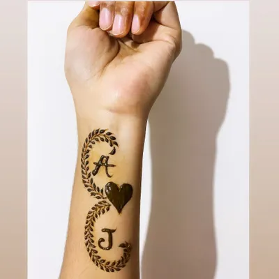 A personalized henna design featuring the initials 'A' and 'J' intertwined with a heart and leafy vines.