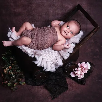 This alert and happy newborn is relaxing in a rustic wooden cart prop. Capturing these awake moments results in engaging and personality-filled portraits.