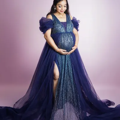 A moment of pure glamour. This expectant mother looks radiant in a sparkling blue gown with a dramatic train, showcasing the high-fashion style we can achieve in your maternity session.