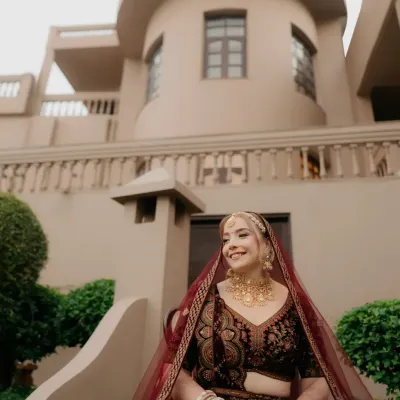 A bride, her eyes filled with stories. This portrait captures her calm, kind, and deep gaze. Her rich maroon lehenga and traditional jewelry are worn with an elegance that is all her own, making for a truly timeless bridal photo.