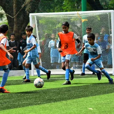 A fantastic action shot from one of our youth tournaments. A player in an orange bib skillfully maneuvers the ball, surrounded by teammates, showcasing the dynamic gameplay we foster.