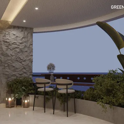 A cozy corner of a curved balcony, designed as a small breakfast nook or coffee spot. The textured stone wall, candle lanterns, and surrounding plants create a warm and intimate setting.