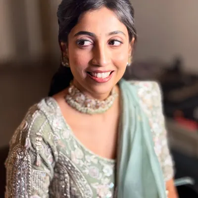A candid, happy shot of my bride Neha at her reception. Her minimal glam makeup features a soft pink eyeshadow and a radiant base that glows under the lights, perfectly matching her pastel green lehenga.