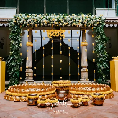 A stunning Haldi setup at the heritage venue Angana, The Courtyard. The decor is rich with traditional elements, including vibrant marigolds, lush tropical leaves, and classic metal props.