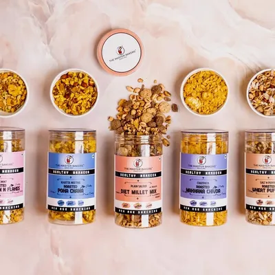 Our healthy namkeen range is your perfect snack partner. This vibrant flat lay shows our variety, including roasted Diet Millet Mix, Poha Chivda, and Sweet Puff Mix, all light, nutritious, and irresistibly tasty.