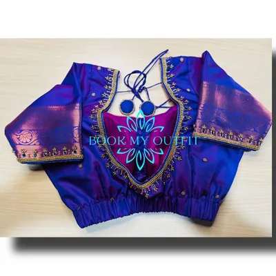 This custom-stitched blouse shows a unique cutout back design with elegant tie-ups and pom-poms. The gold zari border adds a traditional touch, and I ensure the fit is flawless for a comfortable and stylish look.