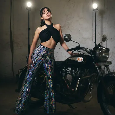 A full-length view of the edgy promotional look for Divya Khosla Kumar. The sequined flared pants and black halter top create a bold silhouette perfect for a film promotion.