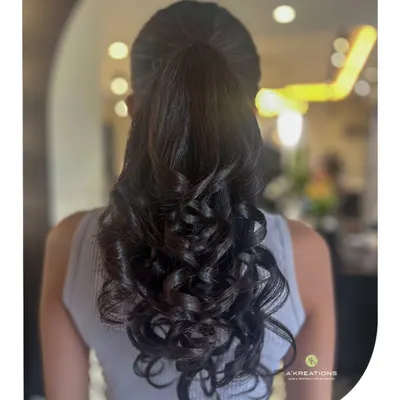 A classic high ponytail elevated with bouncy, perfectly formed curls. This hairstyle is both glamorous and practical for a long night of celebration.