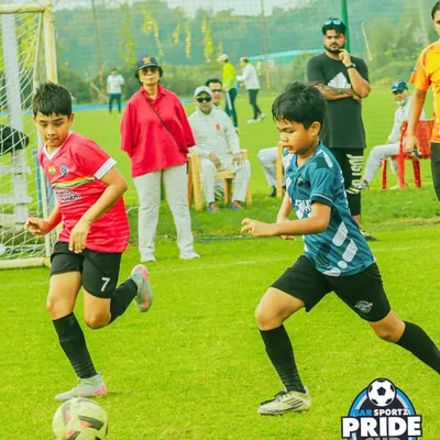 Two young players from opposing teams challenge for the ball during a fast-paced Pride Cup match, demonstrating focus and competitive spirit.