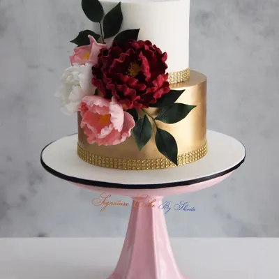 A classic and signature design of mine, this white and gold two-tiered cake is adorned with handmade sugar flowers. It's a timeless choice for an elegant engagement or wedding celebration.
