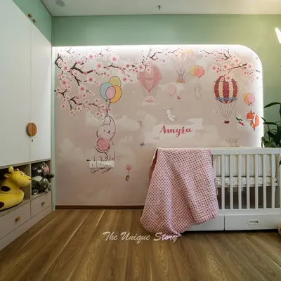 A dreamy nursery for baby Amyra, featuring a custom wall mural of bunnies and hot air balloons. We designed a floor-to-ceiling wardrobe with integrated open cubbies for easy access to toys, combining whimsical design with practical storage.