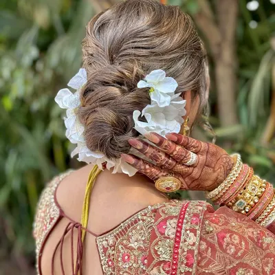 A detailed shot of a classic bridal updo, featuring a textured bun adorned with beautiful white flowers.