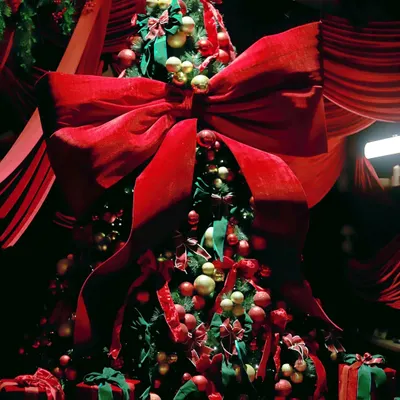 A magnificent Christmas tree adorned with a giant red velvet bow, red and gold ornaments, and surrounded by beautifully wrapped presents. This is the centerpiece of a dramatic, all-red holiday theme.