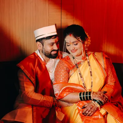 An intimate portrait of a Maharashtrian couple on their wedding day. The warm, dramatic lighting highlights their traditional attire and the quiet connection between them.
