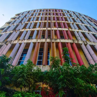 The sweeping curve of the K.J. Somaiya College facade is a signature element of this project. This upward-looking shot emphasizes the scale and rhythmic pattern of the colorful fins, which serve as a key component of the building's passive climate control strategy.