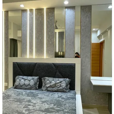 This master bedroom features a dramatic back wall with textured grey panels, vertical light strips, and mirrors to create an illusion of space. The geometric upholstered headboard adds a modern, luxurious touch.
