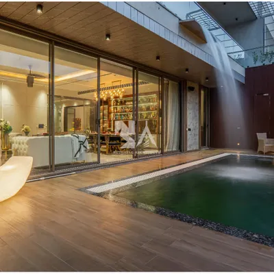 This poolside deck, crafted from warm wood, provides a seamless transition from the indoor living area to the outdoor oasis. A sculptural, moon-shaped lamp adds a touch of artistry and provides gentle illumination for evening gatherings.