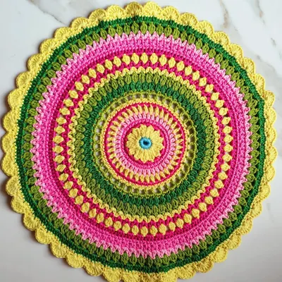 This is the beautiful Viola mandala, a free pattern I found and loved making. I used knitting cotton and a 3.5mm hook to create this vibrant piece with rings of pink, green, and yellow.