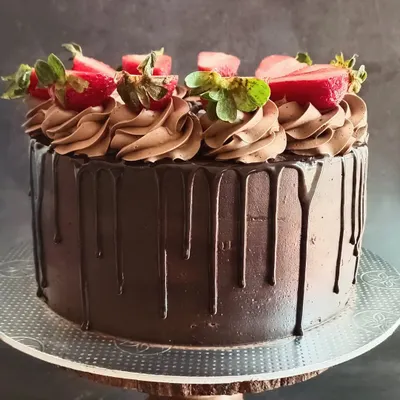 My Death by Chocolate cake is a crowd-pleaser, featuring a moist chocolate sponge, rich chocolate frosting, and a glossy ganache drip. It's topped with fresh strawberries for a perfect flavor combination.